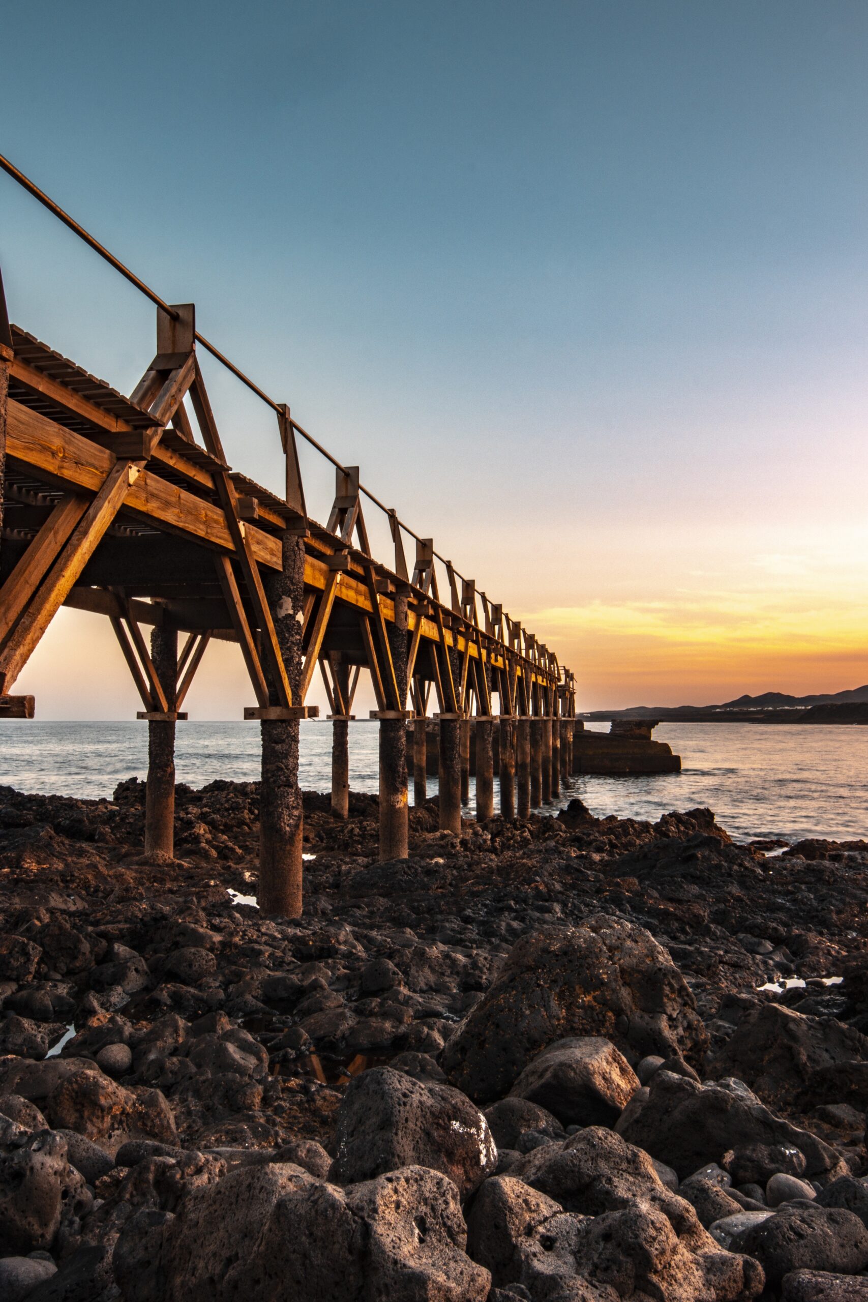 Wooden Bridge on a Tropical Island Wooden bridge extending across a tropical island landscape surrounded by water and greenery
