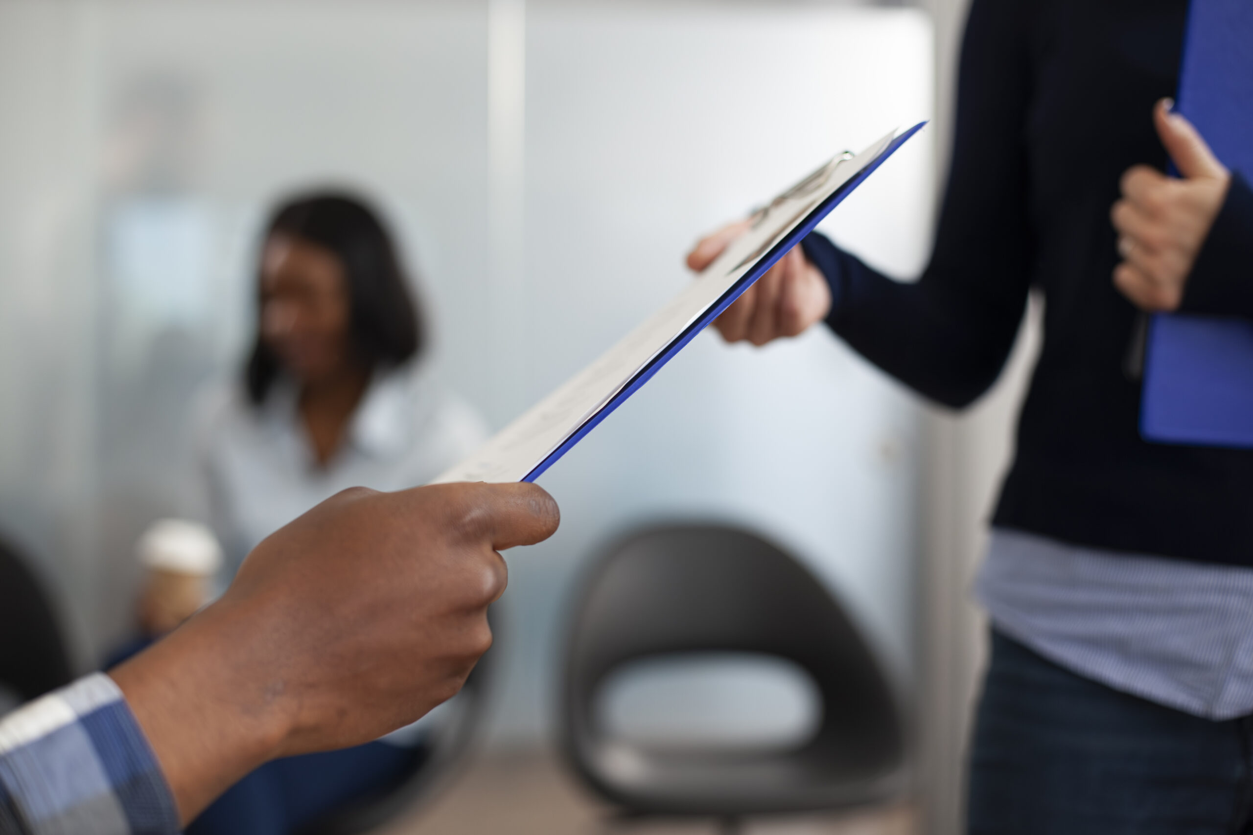 People Reviewing a Document During a Workplace Meeting Two people reviewing a document on a clipboard during a workplace meeting.